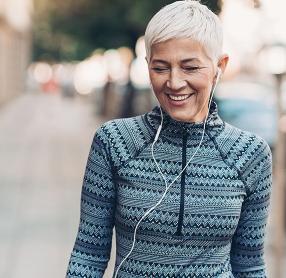 Senior woman walking on street with headphones in