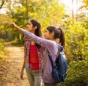 Two girls with hearing aids in woods during autumn