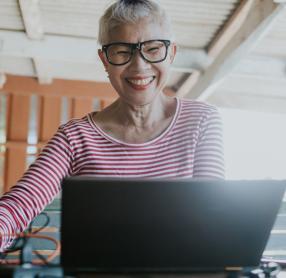 Elderly woman smiling while on her laptop